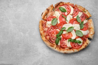 Photo of Delicious Caprese pizza with tomatoes, mozzarella and basil on light grey table, top view. Space for text