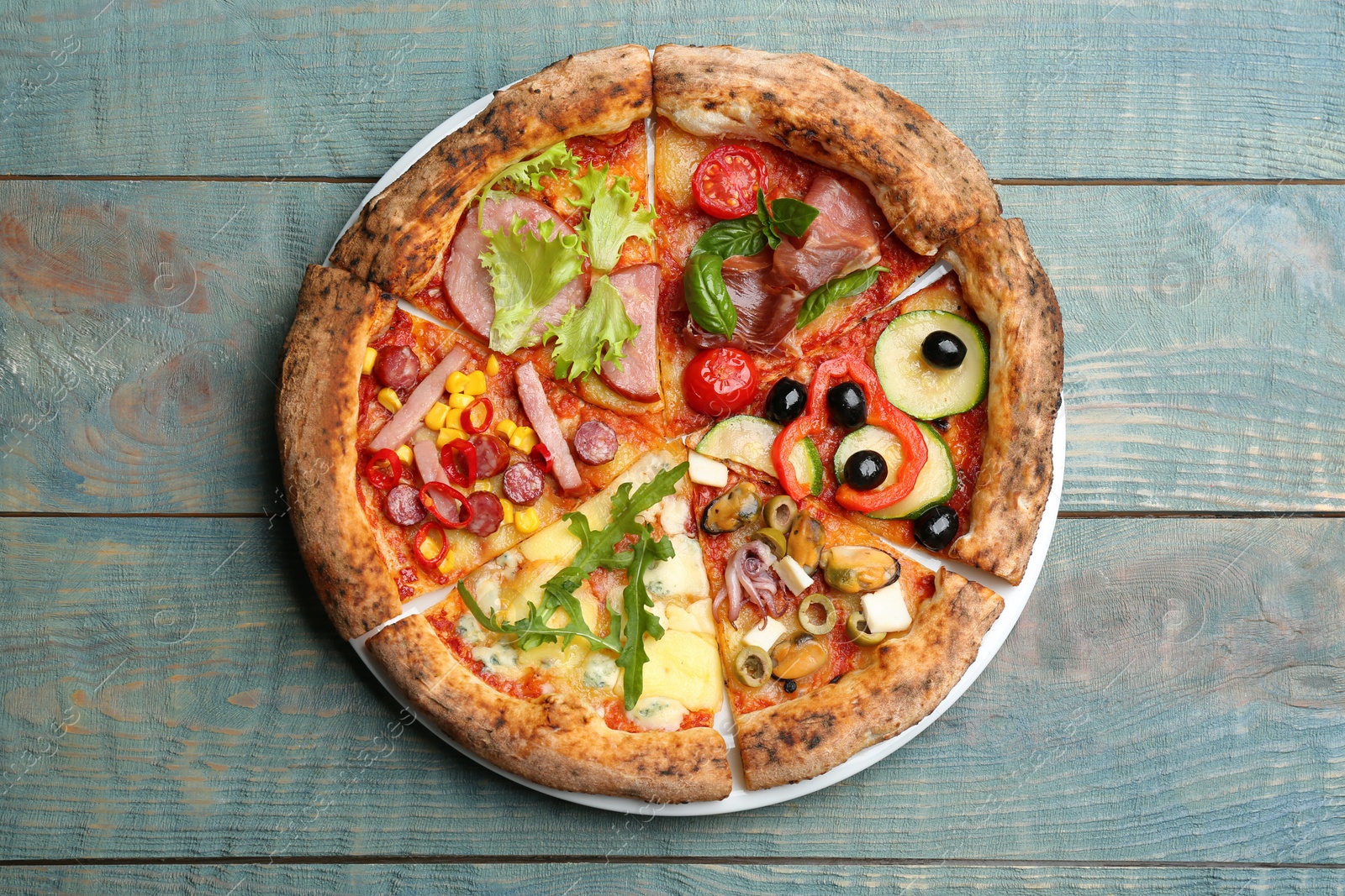 Photo of Slices of different delicious pizzas on blue wooden table, top view