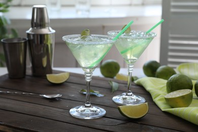 Photo of Delicious Margarita cocktail in glasses and lime on wooden table