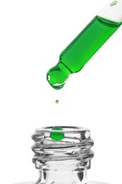 Dripping green facial serum from pipette into glass bottle on white background, closeup