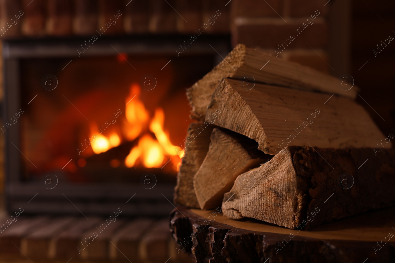 Photo of Pile of wood and blurred fireplace on background, space for text. Winter vacation