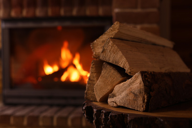 Pile of wood and blurred fireplace on background, space for text. Winter vacation