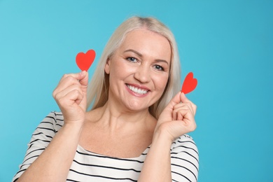 Photo of Portrait of mature woman with decorative paper hearts on color background
