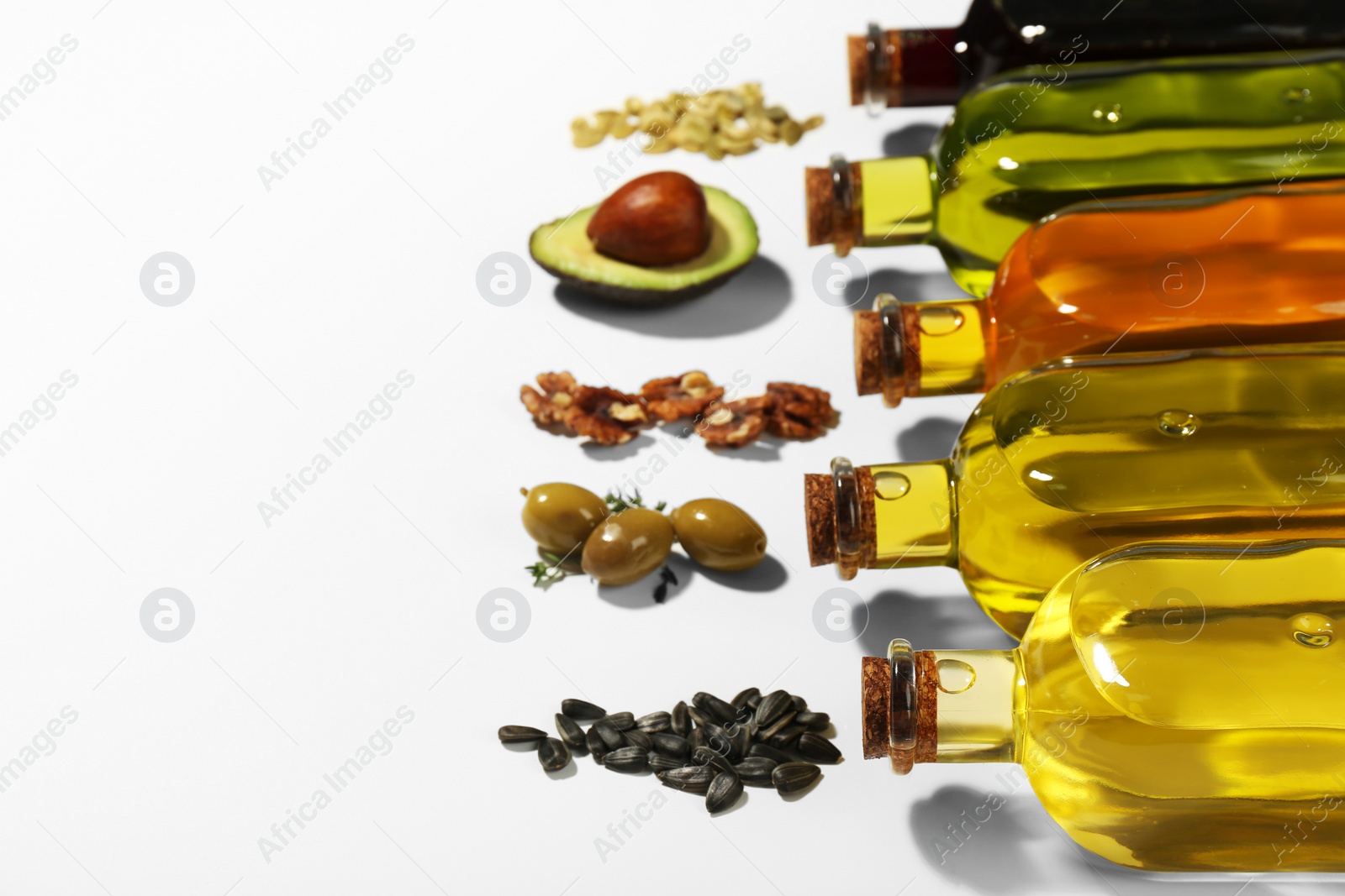 Photo of Vegetable fats. Different cooking oils in glass bottles and ingredients on white background, space for text