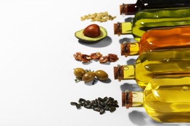 Photo of Vegetable fats. Different cooking oils in glass bottles and ingredients on white background, space for text