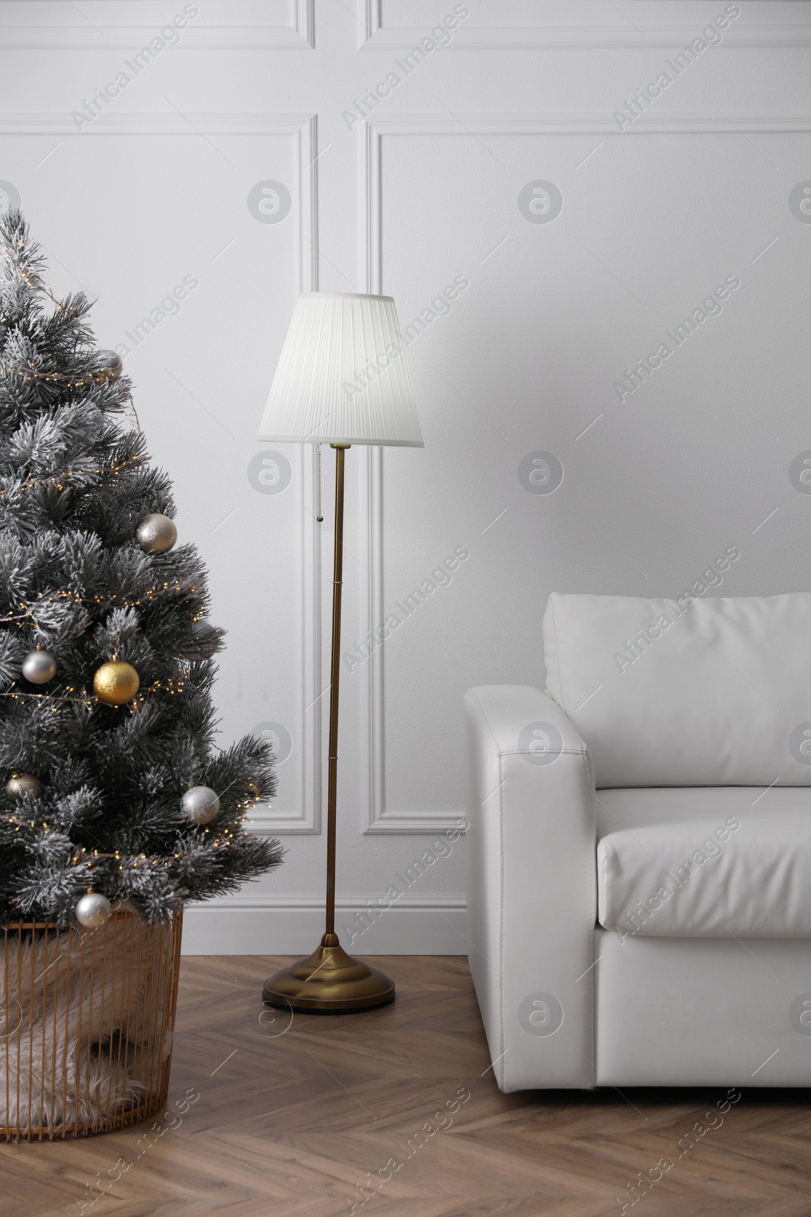 Photo of Christmas tree near sofa against in room. Interior design