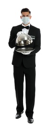 Photo of Waiter in medical face mask holding tray with lid on white background