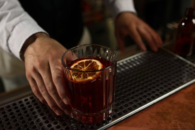 Photo of Bartender with fresh alcoholic cocktail at bar counter, closeup. Space for text
