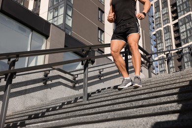 Photo of Man running down stairs outdoors on sunny day, closeup. Space for text