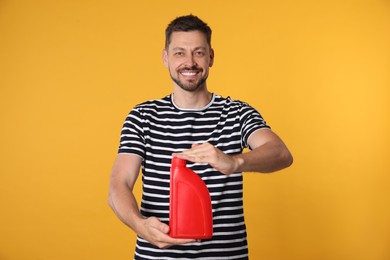 Photo of Man holding red container of motor oil on orange background