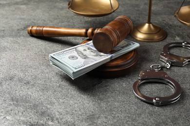 Judge's gavel, money, handcuffs and scales of justice on grey table