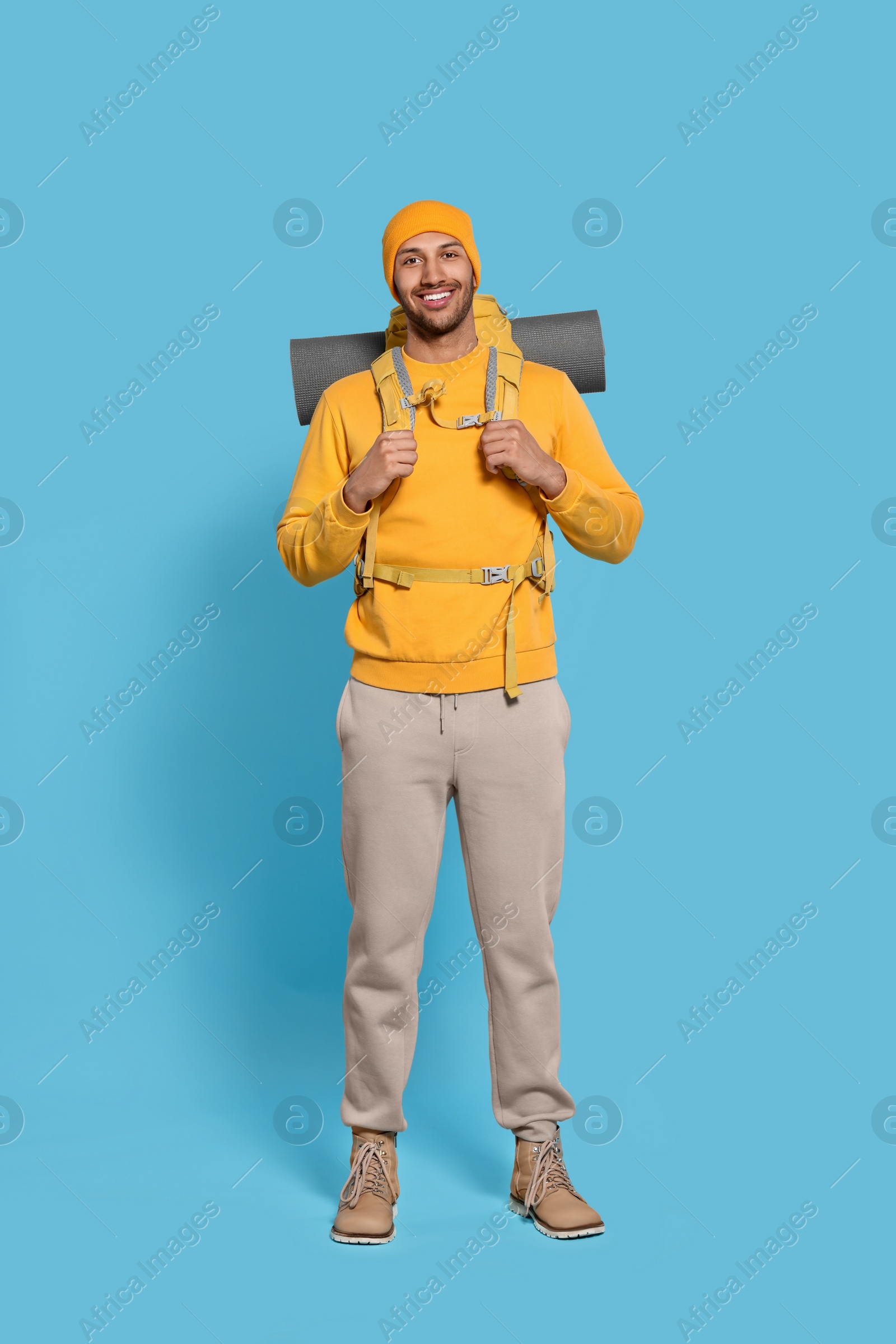 Photo of Happy tourist with backpack on light blue background