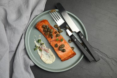 Photo of Delicious salmon with capers and sauce served on dark table, top view