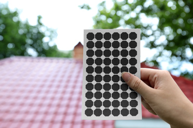 Photo of Woman holding solar panel near building outdoors, closeup