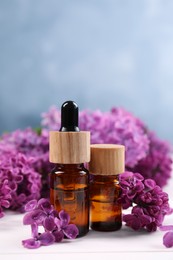 Cosmetic products and lilac flowers on white wooden table, closeup