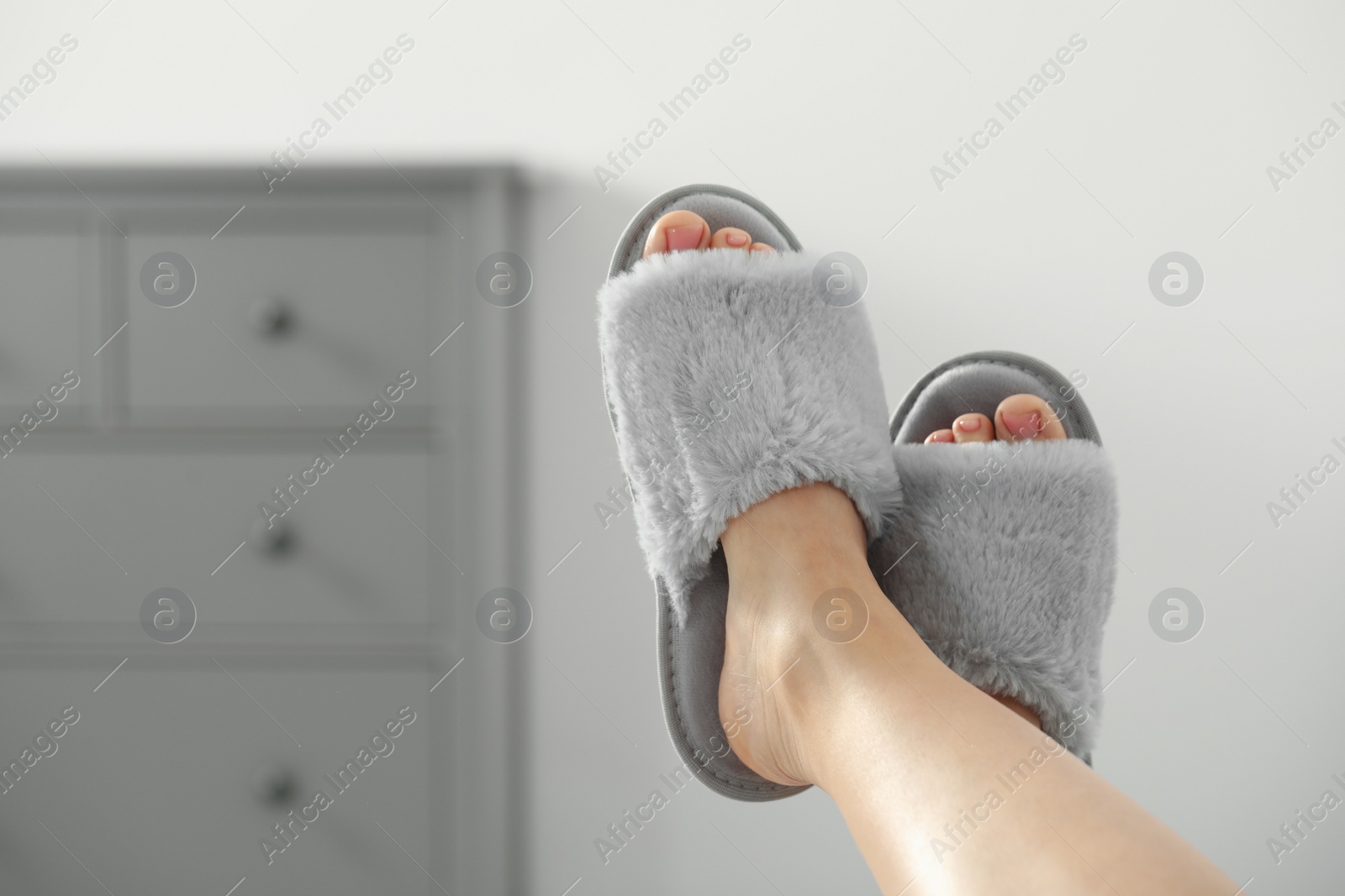 Photo of Woman wearing soft comfortable slippers at home, closeup. Space for text