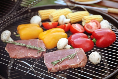 Photo of Fresh steaks and vegetables on barbecue grill, closeup