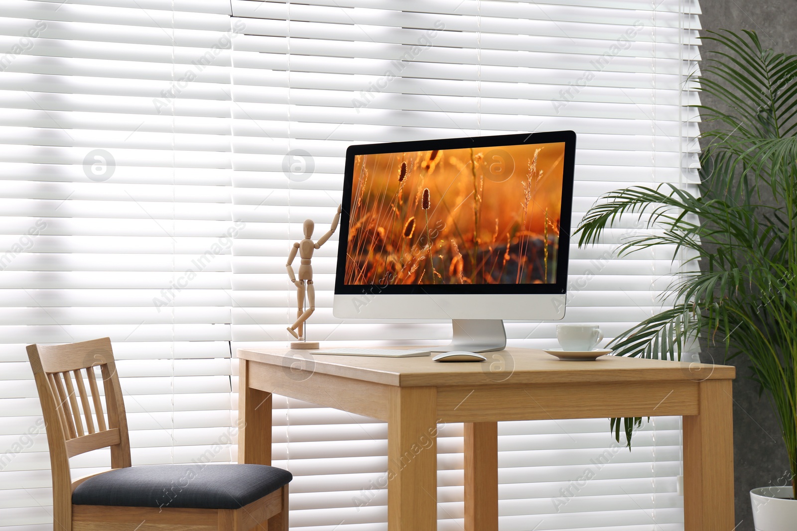 Photo of Modern PC on table near window with blinds in room