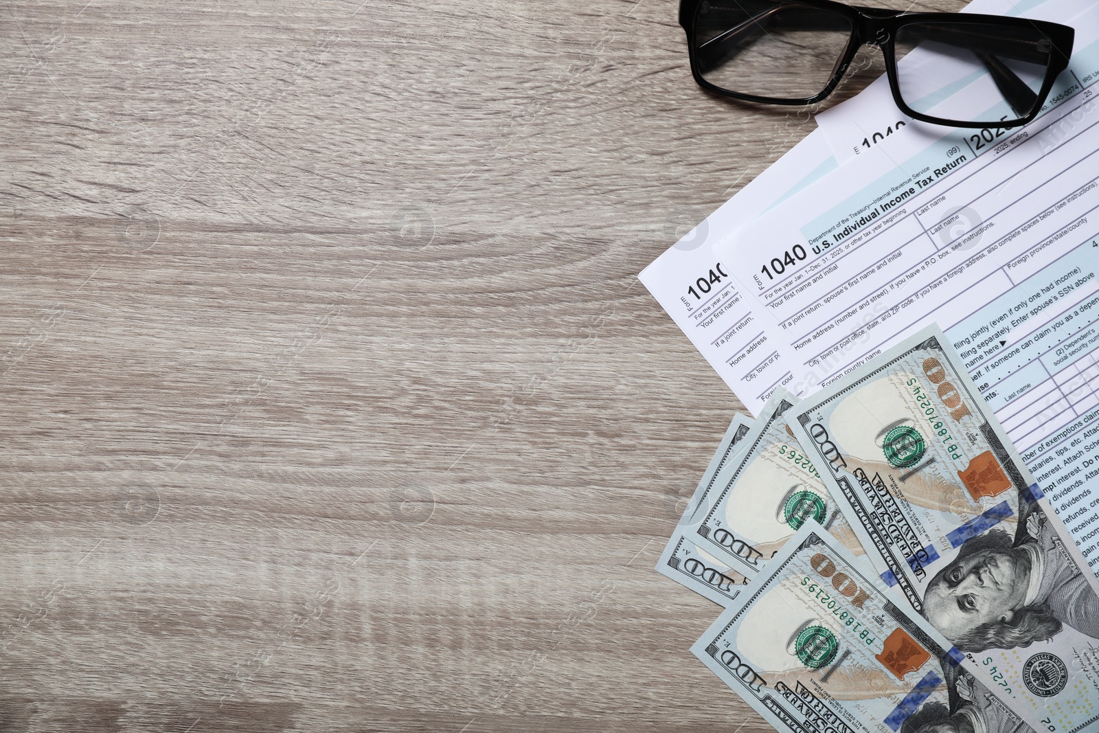 Photo of Payroll. Tax return forms, dollar banknotes and glasses on wooden table, flat lay. Space for text