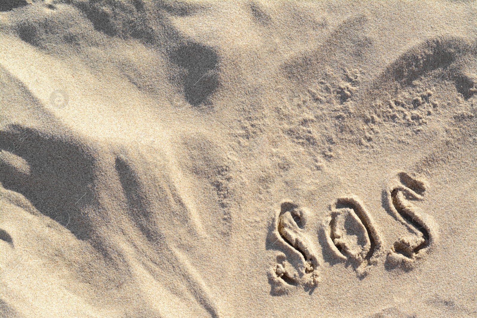 Photo of SOS message written on sandy beach outdoors, top view. Space for text