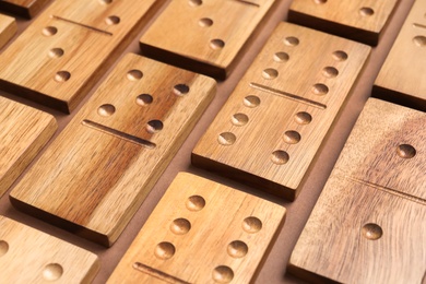 Set of wooden domino tiles on brown background, closeup