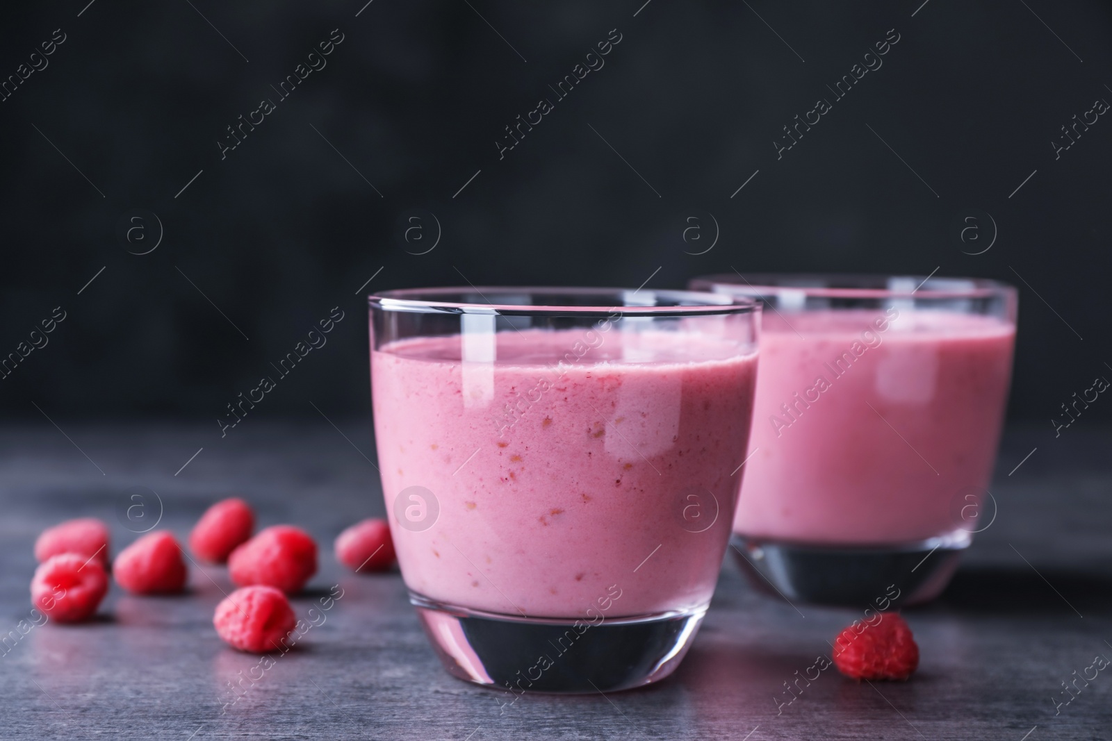 Photo of Delicious smoothie in glasses and fresh raspberries on table