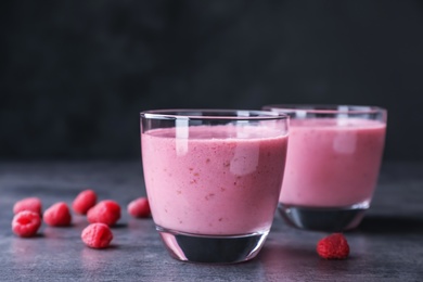 Delicious smoothie in glasses and fresh raspberries on table