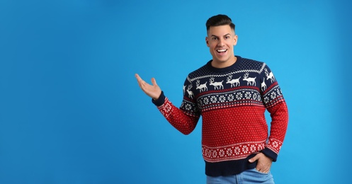 Photo of Happy man in Christmas sweater on blue background