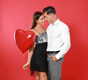 Photo of Beautiful couple with heart shaped balloon on red background