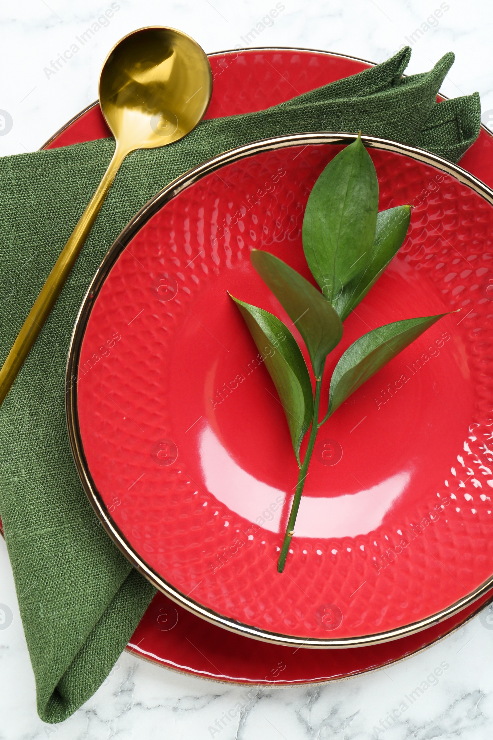 Photo of Stylish ceramic plates, spoon, napkin and floral decor on white marble table, top view