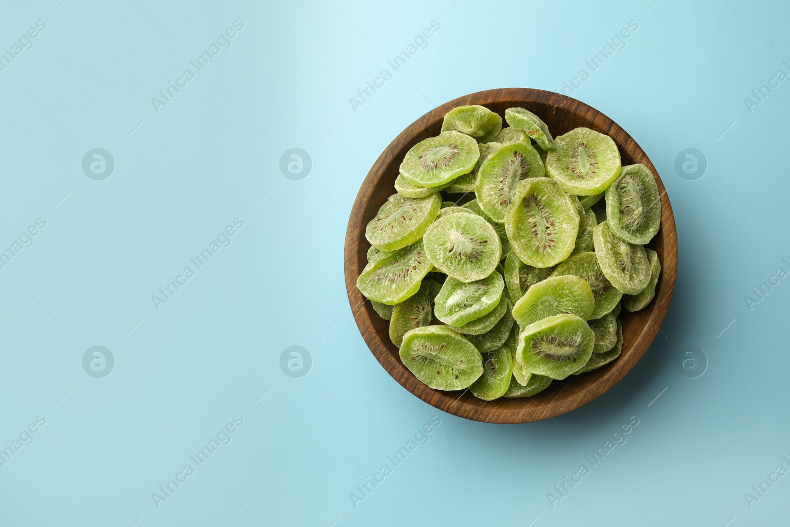 Photo of Bowl of dried kiwi on color background, top view with space for text. Tasty and healthy fruit