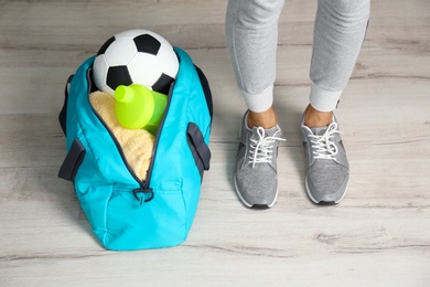 Photo of Young man in sportswear and bag with gym equipment indoors