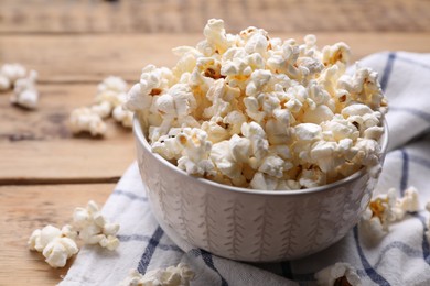 Photo of Bowl of tasty popcorn on wooden table, closeup. Space for text