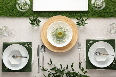 Elegant table setting with green plants on light cloth, flat lay