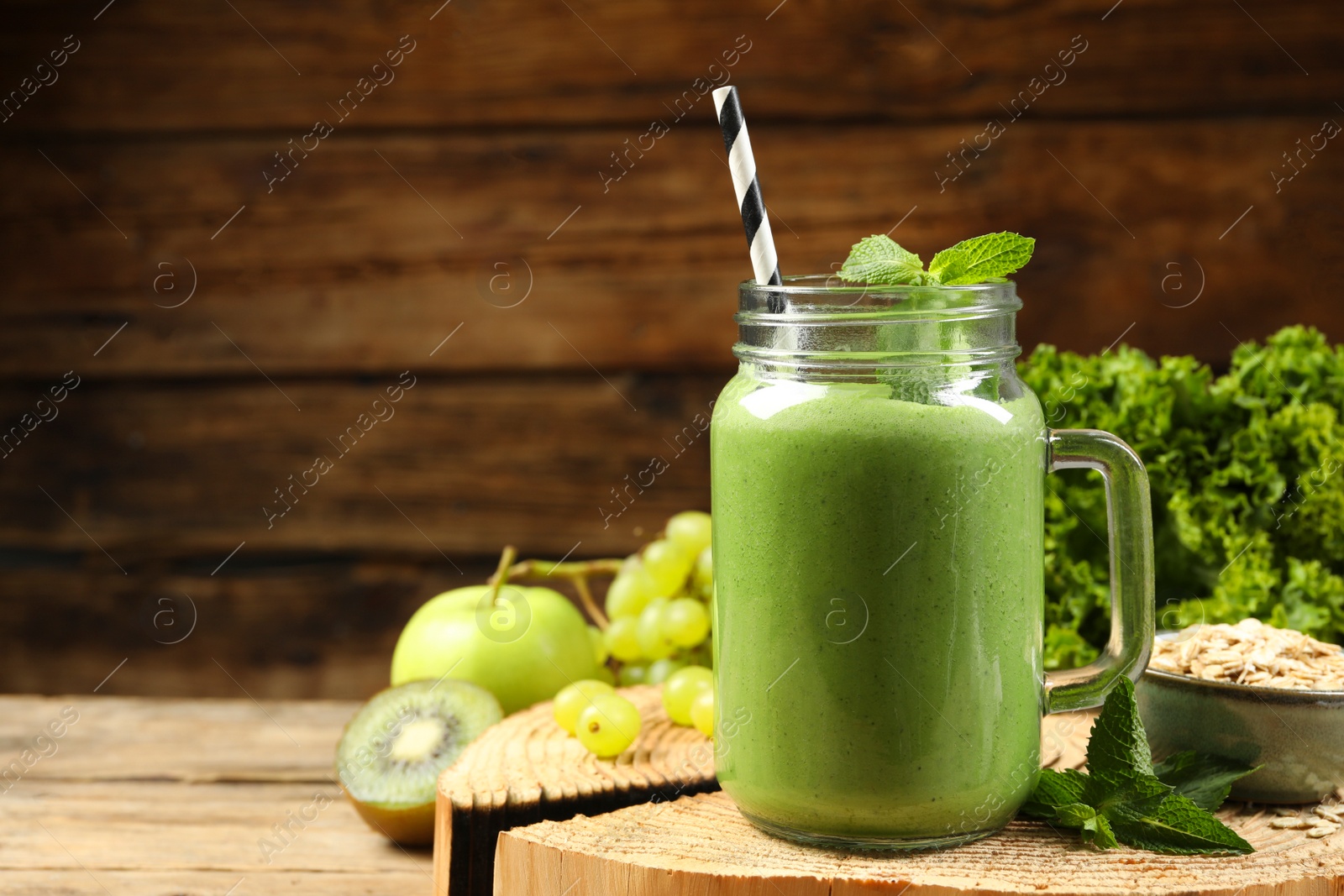 Photo of Mason jar of fresh green smoothie and ingredients on wooden table, space for text