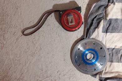 Circular diamond blade and measuring tape on chipboard, flat lay. Tiles installation process
