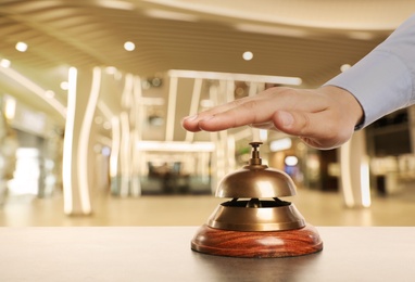 Man ringing hotel service bell on blurred background, closeup