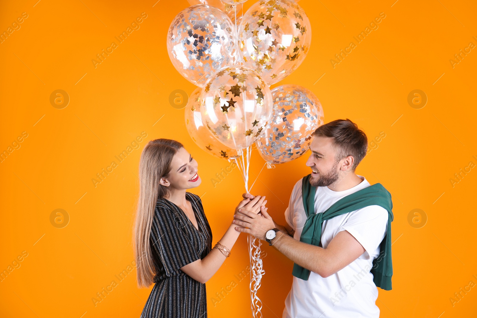 Photo of Young couple with air balloons on color background