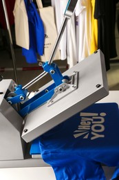 Photo of Printing logo. Heat press with blue t-shirt on table