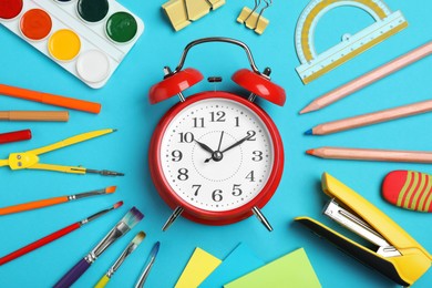Photo of Flat lay composition with alarm clock and different stationery on light blue background. School time