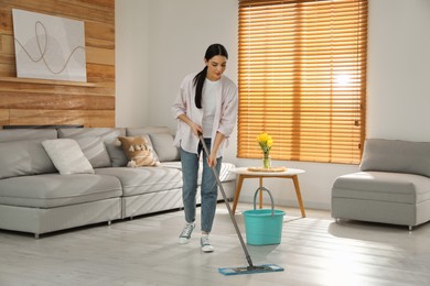 Photo of Woman cleaning floor with mop at home