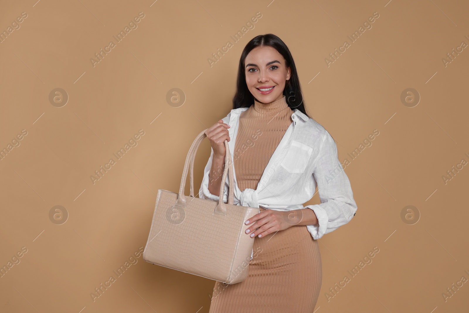 Photo of Young woman with stylish bag on beige background, space for text