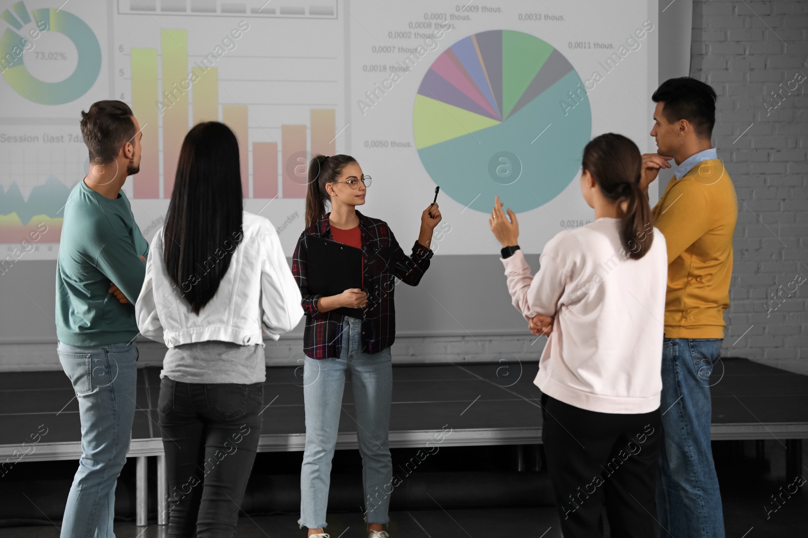 Photo of Young people having business training in conference room with projection screen