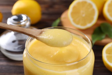 Taking delicious lemon curd from glass jar at table, closeup