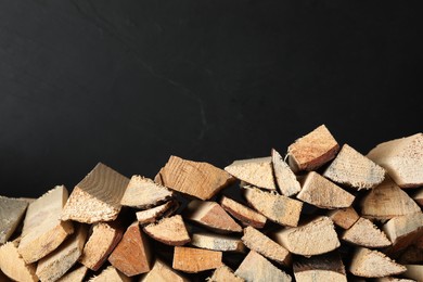 Cut firewood on black background. Space for text