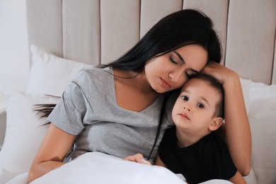 Photo of Depressed single mother with child in bed at home