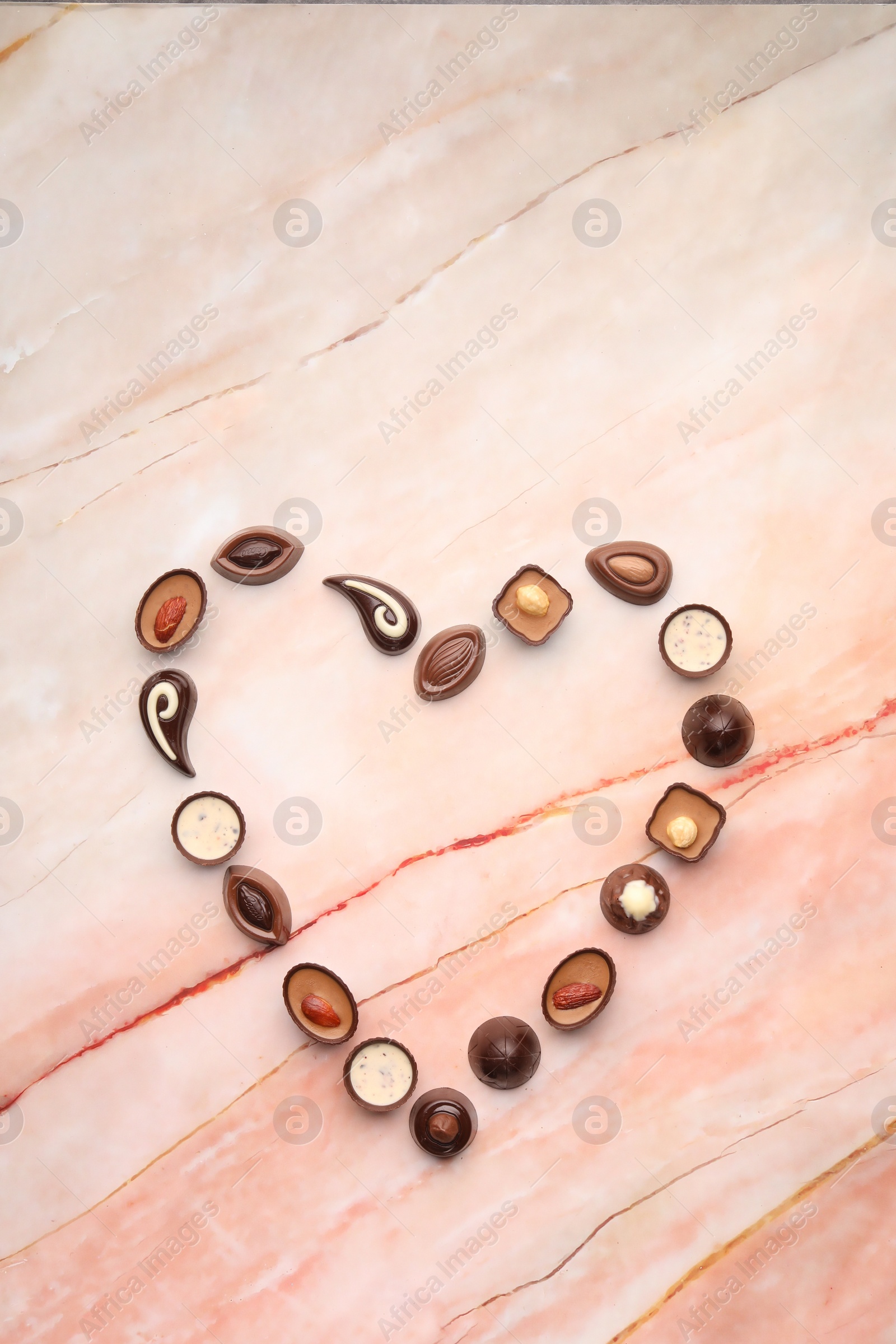 Photo of Heart made with delicious chocolate candies on marble table, top view
