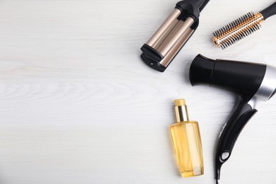 Flat lay composition with hairdressing equipment on white wooden background. Space for text