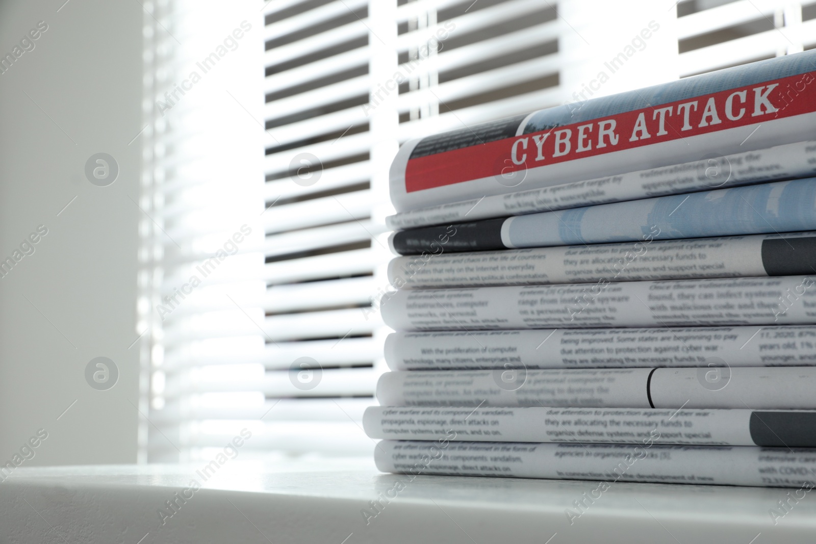 Photo of Newspapers with headline CYBER ATTACK stacked on white table indoors. Space for text