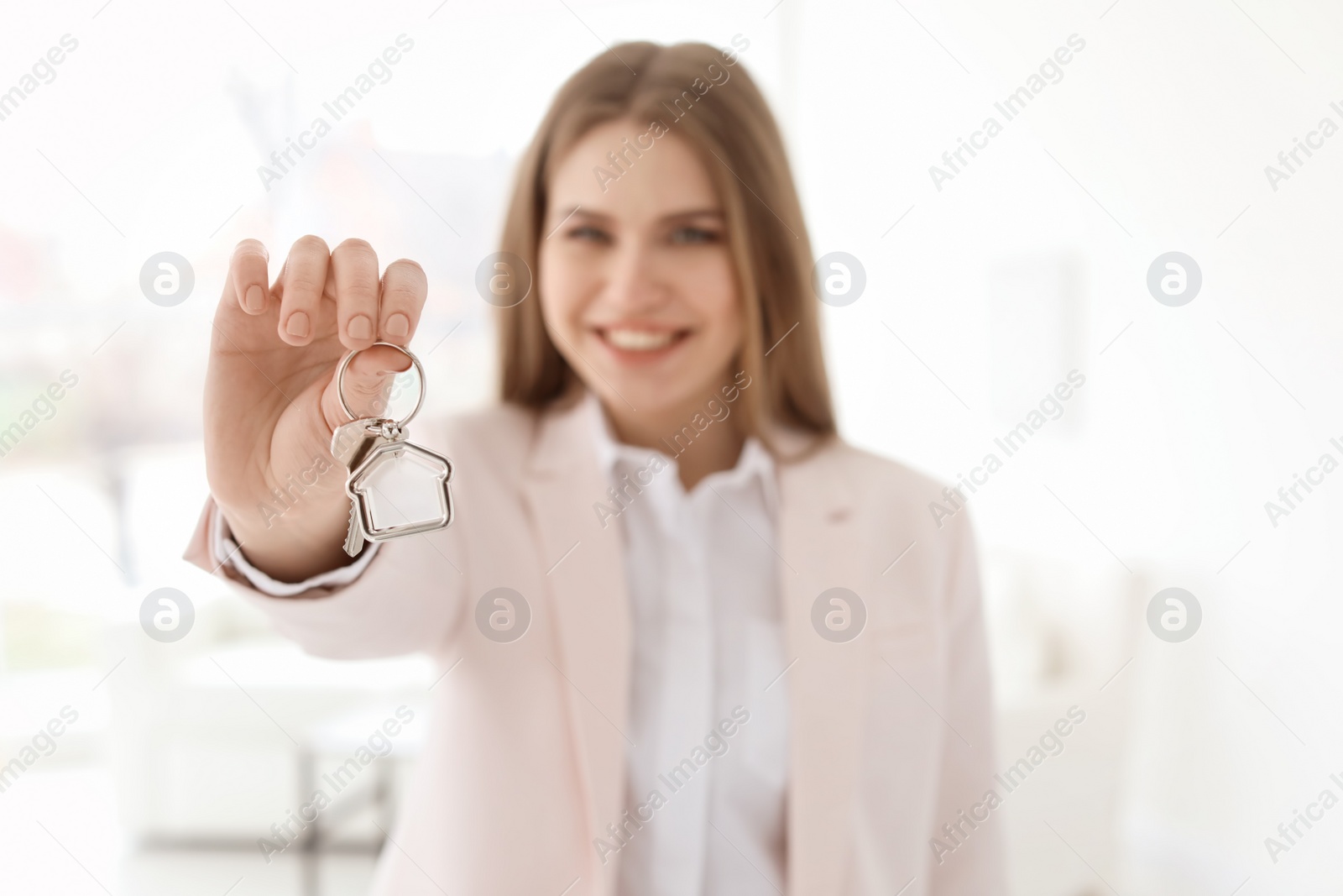 Photo of Beautiful real estate agent with key indoors, closeup